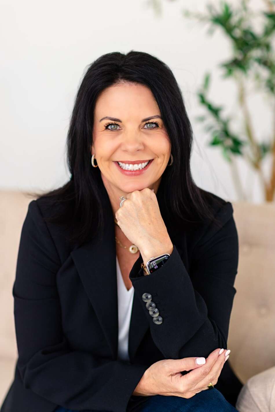 Jodi Ashcraft seated, smiling, in a black blazer with her hand under her chin